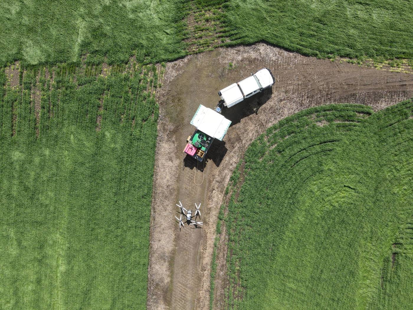 Aerial view of a Rencon spray drone and support vehicles at a paddock